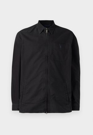 Zwarte langwerpige zip-up shirtjack met kraag, borstzak met een klein geborduurd logo en twee zijzakken.