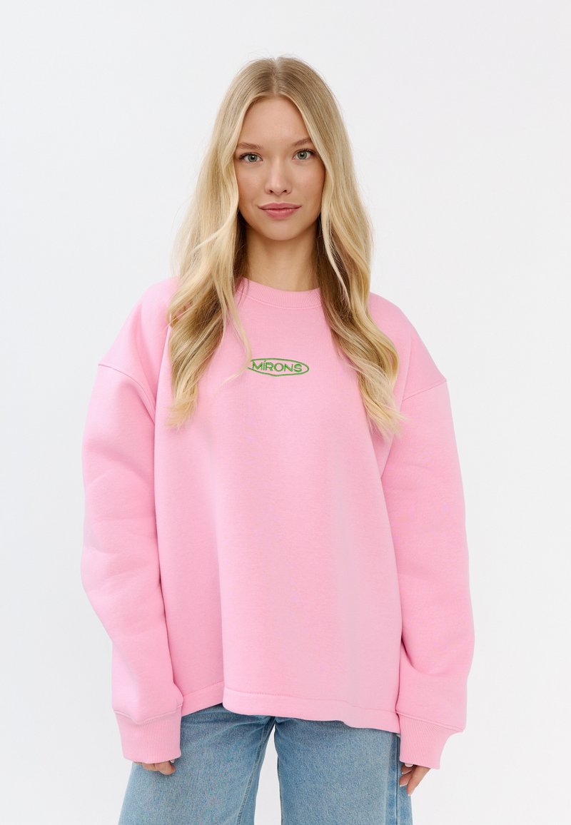 Felpa oversize rosa con polsini e fondo a costine, caratterizzata da un logo ricamato verde "MIRONS" sul petto. Texture del tessuto morbida.