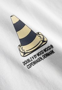 Fehér anyagon egy bézs és tengerészkék csíkos közlekedési kúpot ábrázoló nyomtatott grafika látható, rajta a "DOUBLE A BY WOOD WOOD, COPENHAGEN, DENMARK." felirattal.