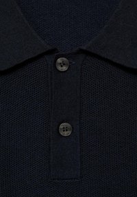 Marineblaues Poloshirt mit strukturiertem Strickdesign, klassischem Kragen und zwei dunklen Knöpfen mit jeweils vier Löchern zum Schließen.