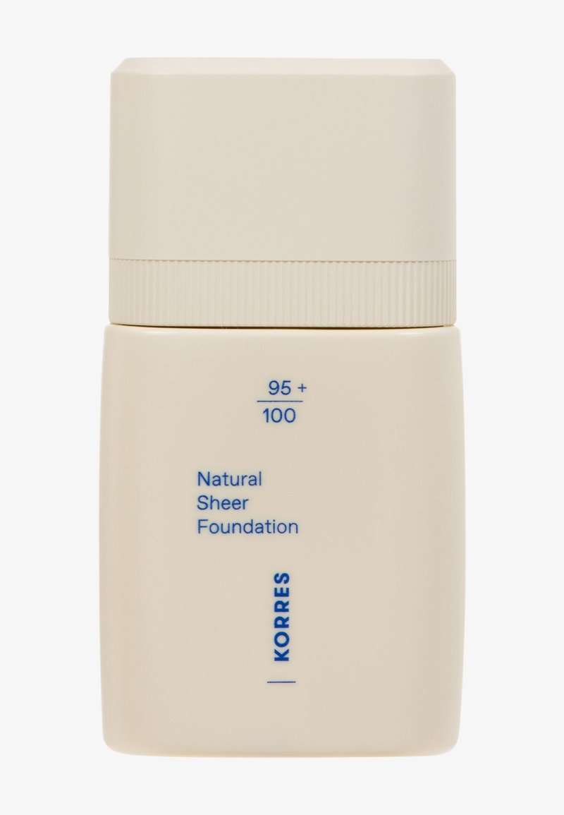 Bottiglia beige con finitura opaca e tappo rotondo. Presenta un testo blu che etichetta il prodotto come "Fondotinta Naturale Sublime" di Korres.