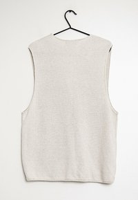 Jasnoszary bezrękawnik z dzianiny wiszący na czarnym haczyku, z teksturowaną powierzchnią i okrągłym dekoltem bez dodatków.