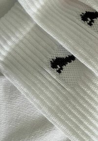 Weiße gerippte Socken mit einem schwarzen Silhouetten-Design. Die Textur ist glatt mit einem gewebten Muster und einem gleichmäßigen, weichen Finish.