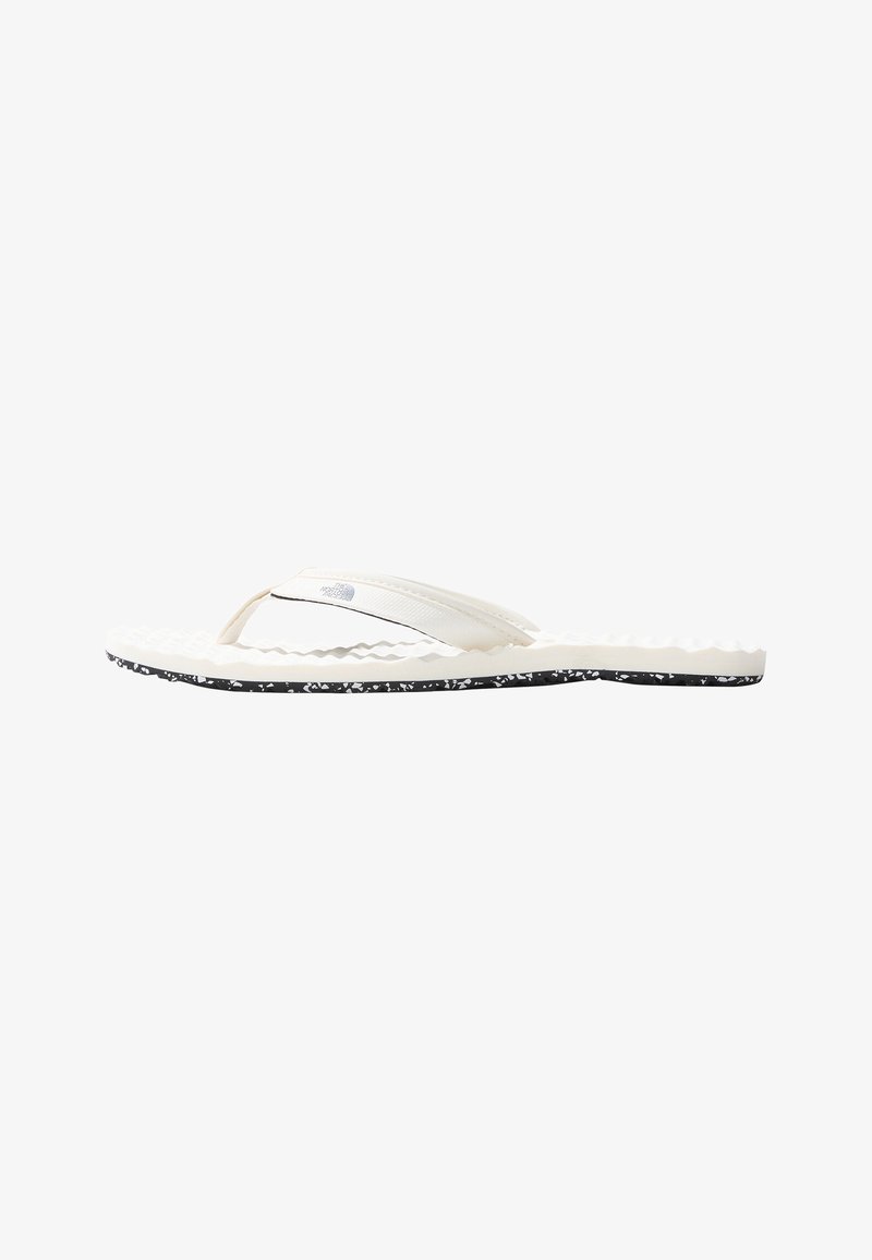 White flip-flop sandal with a textured sole and black speckled bottom. Features a smooth, slender strap with a logo accent.