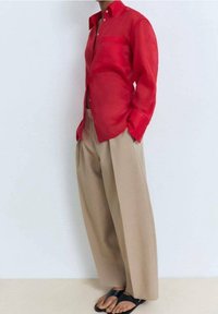 Rode doorschijnende overhemd met lange mouwen, een kraag en een borstzakje, gecombineerd met beige wijde broekspijpen en zwarte sandalen.
