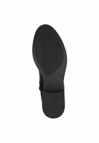 Suela de zapato negra con forma suave y redondeada. Presenta una superficie de goma texturizada para mayor agarre y un pequeño tacón en la parte trasera.