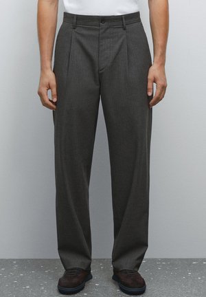 Gray pinstriped trousers made of fabric, featuring a pleated front and a straight-leg design. Worn with a white t-shirt and dark shoes.