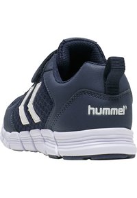 Chaussure de sport bleu marine en tissu en maille et accents synthétiques, arborant un logo blanc, un design à trois rayures et une semelle en caoutchouc texturé.