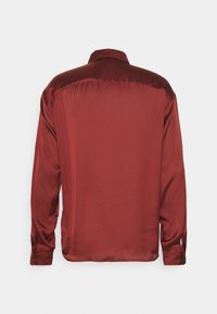 Camicia in raso rosso, maniche lunghe, collo classico, tessuto liscio, polsini con bottoni, vista posteriore, senza motivi o disegni visibili.