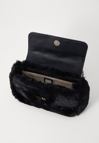 Portafoglio in finta pelliccia nera con una texture morbida, chiusura a pattina e hardware in argento. L'interno presenta una fodera di colore chiaro e scomparti per carte.