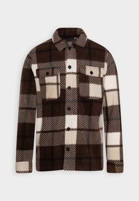 Chaqueta de forro polar de cuadros marrones y crema con cierre de botones en la parte delantera, dos bolsillos en el pecho y botones negros; presenta patrones diagonales en contraste.