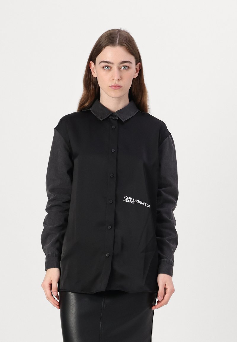 Melna pogājama krekla ar kontrastējošiem tumša denima piedurknēm, izšūts "KARL LAGERFELD JEANS" logo, ar apkakli, gluda tekstūra.