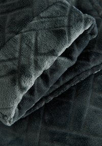 Ciemnoszara, miękka tkanina o miękkiej fakturze z pikowanym wzorem w romby, pokazana w ułożeniu złożonym i warstwowym.