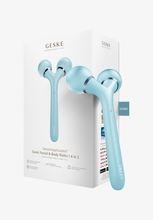 Blå Y-formet sonisk ansigts- og krop rulle med teksturerede massagehoveder ved siden af dens hvide æske med mærket "GESKE German Beauty Tech."