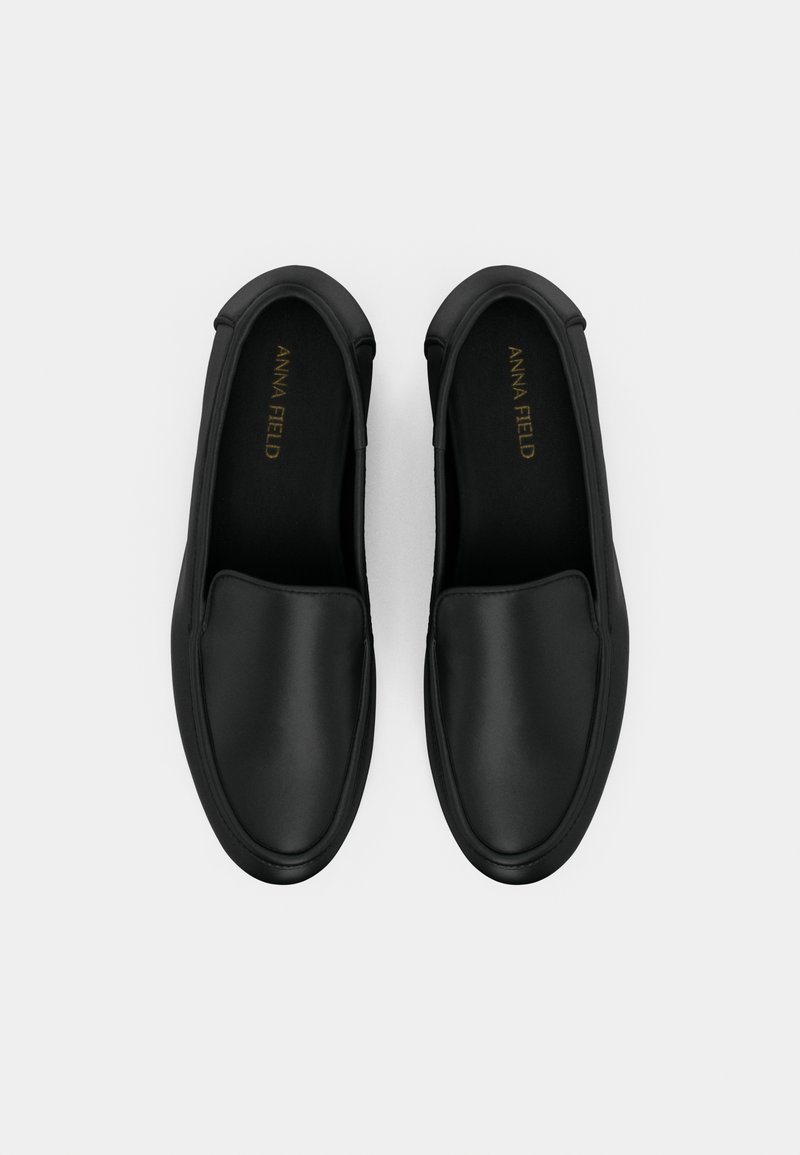 Chaussures noires à enfiler avec une finition en cuir lisse, bout rond, panneaux élastiques sur les côtés et semelle en caoutchouc plate. Marquage doré à l'intérieur.