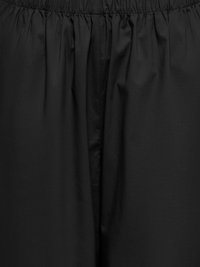 Tissu noir avec ceinture élastique froncée et plis subtils, montrant la texture et un léger éclat.