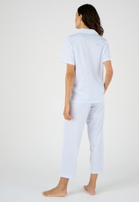 Conjunto de pijama de tiras azules y blancas de manga corta, que incluye una camisa con cuello y pantalones recortados. Tejido suave con un corte relajado.