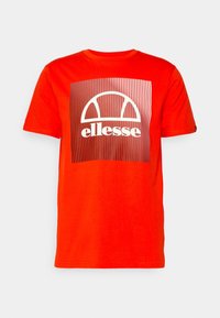 Punainen puuvillapaita lyhyellä hihalla, jossa on keskeinen graafinen kuvio valkoisilla ja hopeisilla raidoilla, korostaen brändin nimeä "ellesse."