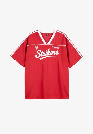 Czerwona sportowa koszulka wykonana z tkaniny, z krótkimi rękawami, dekoltem w serek, białymi akcentami i napisem "Strikers" na przodzie.
