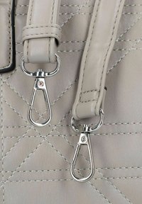 Sangle de sac en cuir gris avec des clips en métal argenté, présentant une texture matelassée et un coutu contraste. Deux clips sont visibles, attachés à la sangle.