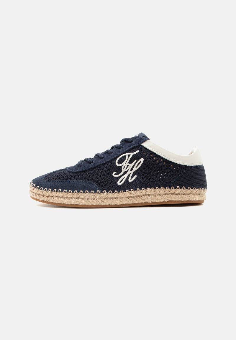Baskets bleu marine à lacets avec col de talon blanc, dessus en tissu tissé, initiales "FH" brodées, et semelle en jute tressée sur une surface plane.