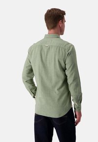 Camicia verde a maniche lunghe con bottoni, realizzata in tessuto testurizzato, con orlo curvo e bottoni sui polsini. Vista posteriore mostrata.
