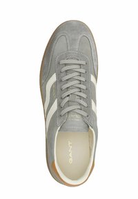 Šedé semišové tenisky s bílými pruhy, kulatou špičkou, texturovanými tkaničkami a hnědou gumovou podrážkou. Zlaté logo na jazyku.