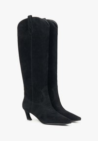 Černé semišové kozačky po kolena s špičatou špičkou a 5 cm podpatkem. Mají tonální švy a dvě poutka na vrchu pro snadné obutí.