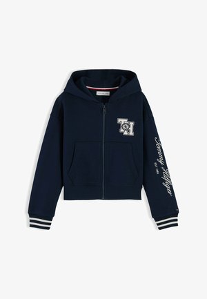 Sweat à capuche bleu marine zippé avec poches avant, poignets rayés, logo "TH" sur la poitrine et texte "Tommy Hilfiger EST 1985" sur la manche.