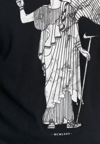 Black fabric features a graphic of a draped figure with marble-like pattern, holding a staff, and wearing sneakers, with lines and pleats.
