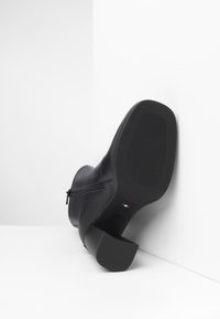 Schwarze Leder-Stiefelette mit einem seitlichen Reißverschluss, quadratischem Absatz und strukturiertem Gummilaufsohle. Verfügt über eine glatte Oberflächenstruktur und minimale Akzente.