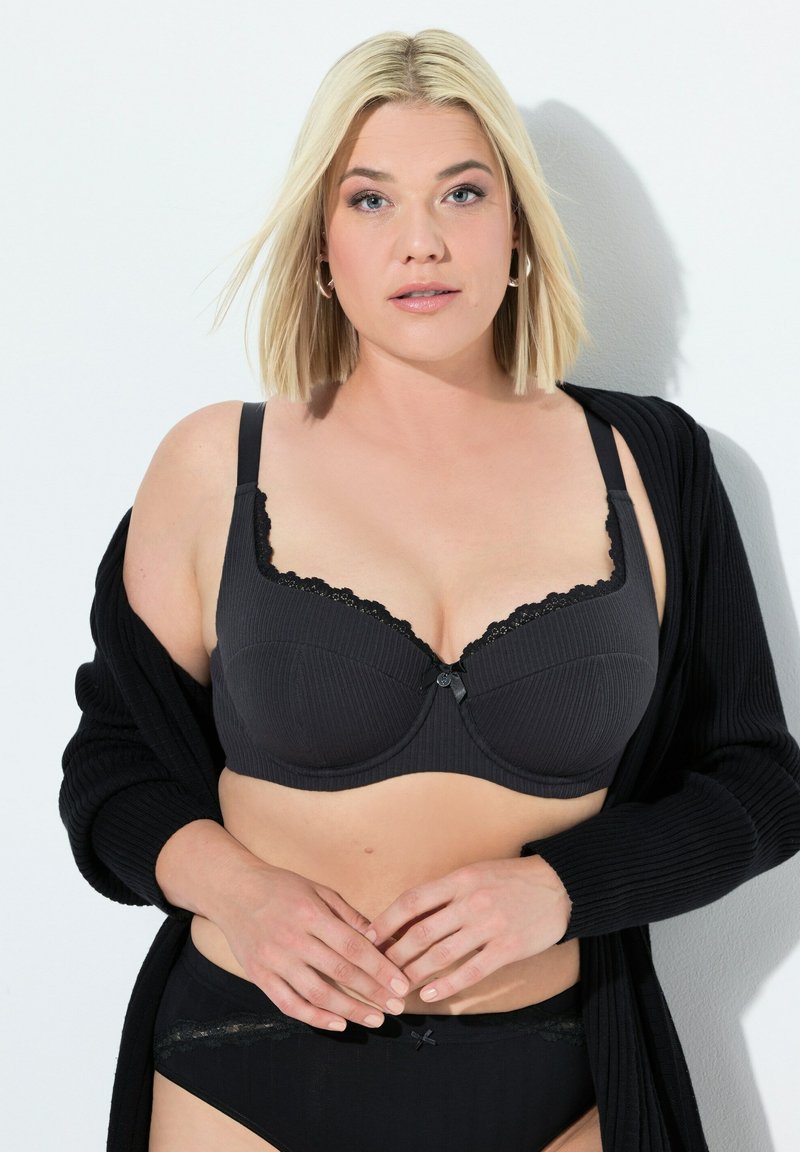 Zwarte bh met ribbelstructuur en kantafwerking, voorzien van een centrale knoopdetail. Gecombineerd met bijpassende hoge taille slip.
