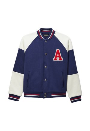 Veste universitaire bleu marine avec manches blanches, lettre rouge et blanche « A » sur la poitrine, col, poignets et bas côtes rayés, et fermeture pression.