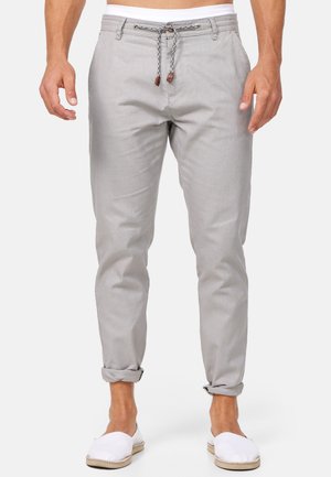 Pantalons en tissu gris clair, effilés, à texture lisse ; avec une taille à cordon de serrage ornée d'accents en bois et des ourlets retroussés.