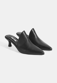Mules noirs à bout pointu avec un petit talon carré. Fabriqués en cuir lisse avec un design sans fermeture, sans matériel ni décorations visibles.