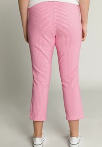 Růžové kostkované cropped kalhoty s hladkou texturou, mají přiléhavý střih a mírně zúžené nohavice. Vhodné pro volný čas.