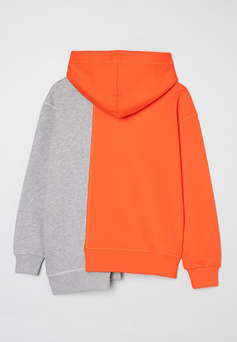 Hoodie mit geteiltem Design: Eine Seite in Grau und die andere in leuchtendem Orange. Hergestellt aus einem weichen Baumwollgemisch, mit gerippten Bündchen.