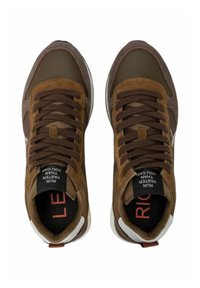 Bruine sportieve sneakers met een mix van gladde en gestructureerde materialen, ronde neuzen, opvallende veters en contrasterende witte accenten.