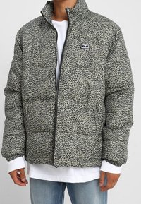 Kurtka ocieplana w kolorze szarym z czarnym motywem panterki. Posiada wysoki kołnierz, zapięcie na zamek i naszywkę z logo na lewej piersi. Miękka w dotyku.