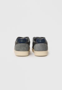 Gray suede and mesh sneakers with a beige rubber sole, featuring a navy accent on the heel and simple stitching details.