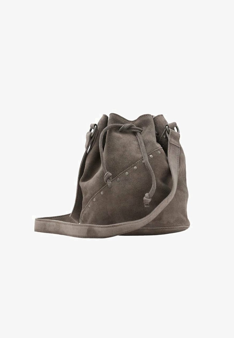Borsa a secchiello in suede grigio con chiusura a coulisse, rifinita con borchie metalliche su un lato e una tracolla piatta e larga. Texture morbida e design casual.