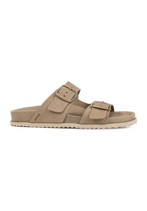 Beige Wildleder-Sandalette mit zwei verstellbaren Schnallenriemen und einer strukturierten Sohle für den Freizeitgebrauch.