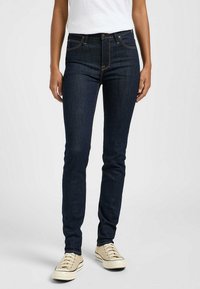 Jeans ajustados en denim azul oscuro. Sus características incluyen una cintura alta, diseño de cinco bolsillos, costuras en contraste y un cierre clásico con botón.