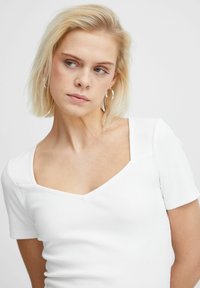 White ribbed short-sleeve top with a square neckline and a fitted silhouette. Smooth texture with minimal seams and clean edges.