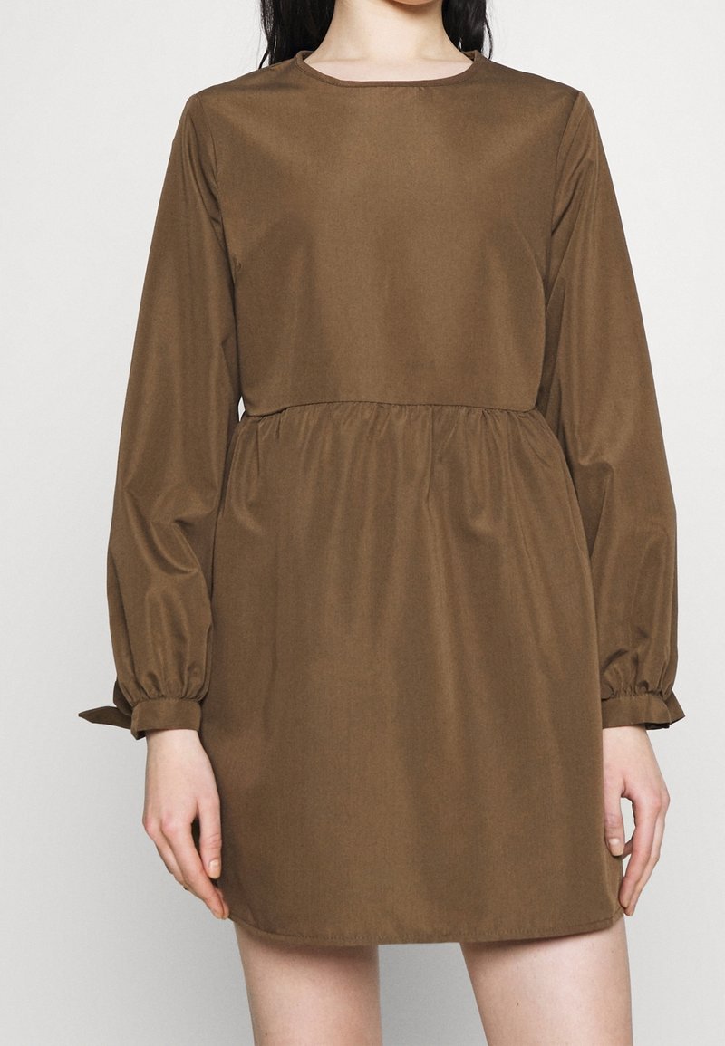 Robe marron à manches longues avec col rond, taille froncée et manches bouffantes, en tissu lisse. L'ourlet se situe au-dessus du genou.
