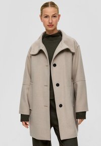 Beige wollen blendjas met een hoge kraag, grote zijzakken, drie knopen en een gestructureerde afwerking. Casual, oversized silhouet.