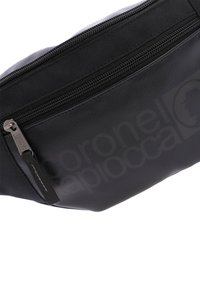 Riñonera negra hecha de cuero sintético con una textura suave, que cuenta con un cierre superior de cremallera y un discreto detalle del logo.