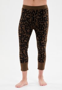 Eng anliegende braune Leggings mit einem schwarzen, auffälligen Textmuster. Gerippter Bund und Bündchen mit glatter Textur.
