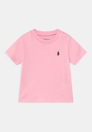 Różowa, krótka koszulka niemowlęca z okrągłym dekoltem i dwoma zatrzaskami na ramieniu, z małym granatowym haftowanym logo gracza polo na piersi.