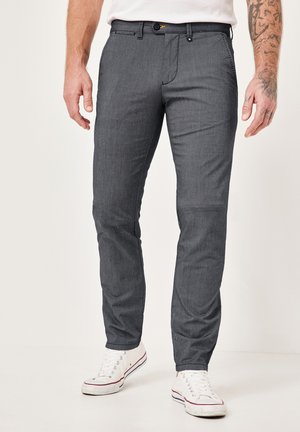 Gray, slim-fit pants made of textured fabric with a subtle pattern, featuring belt loops and a button closure, paired with white sneakers.